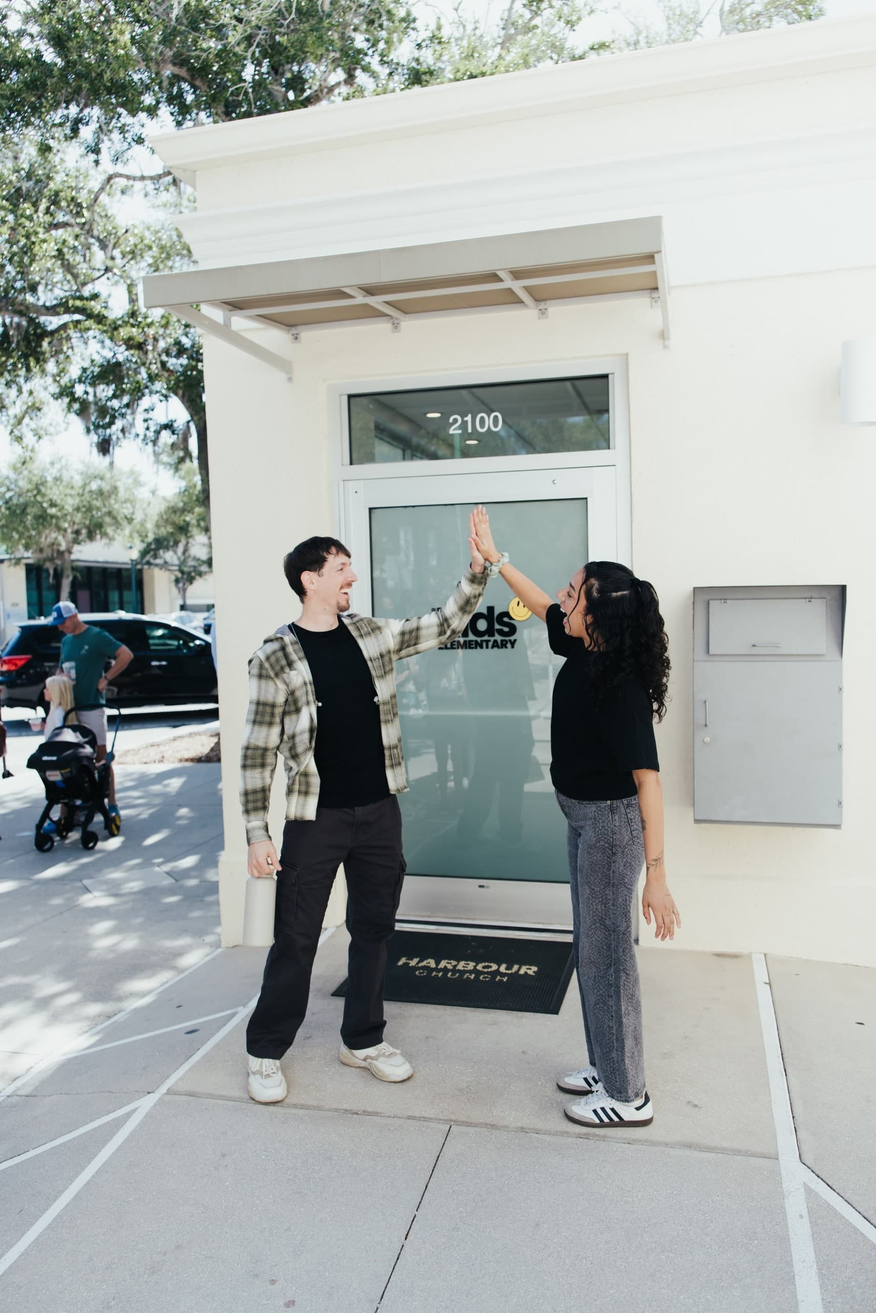 Two Harbour Church team members greeting each other with a high five at the entrance