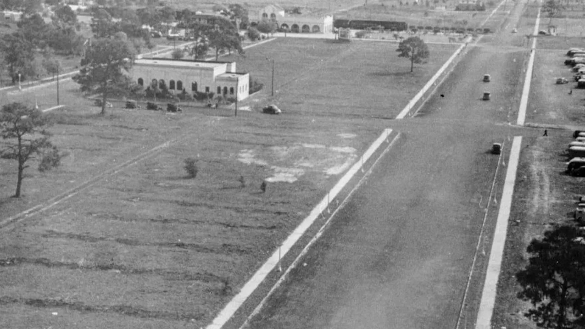 Historic elevated view of the church grounds and Main Street, with early cars along the road.